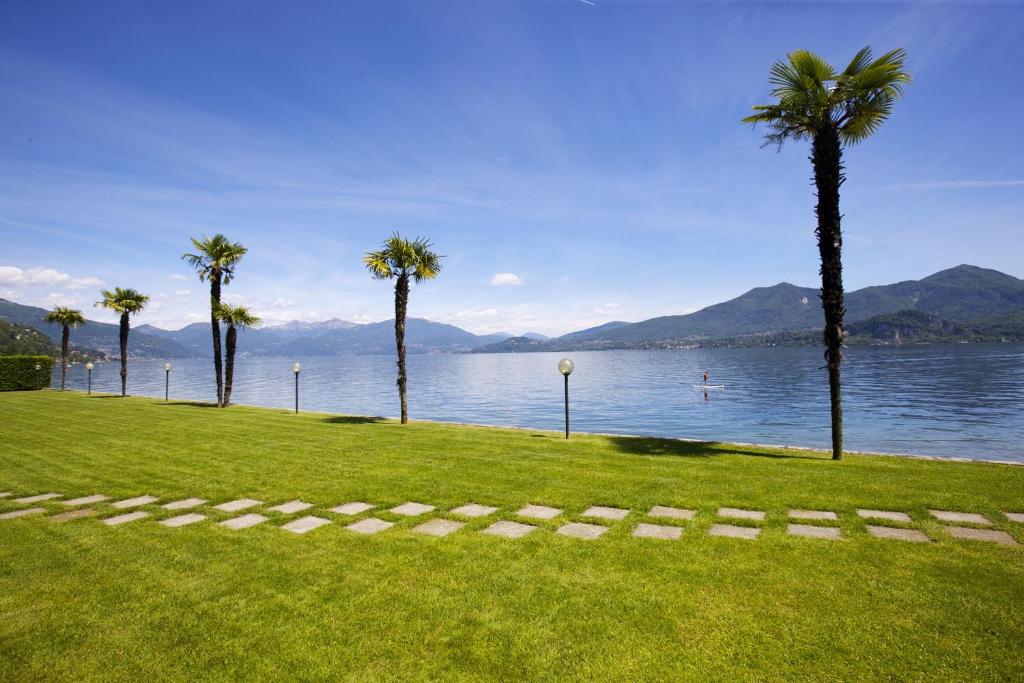 a grassy area with palm trees and a body of water at Yachting Residence in Ghiffa