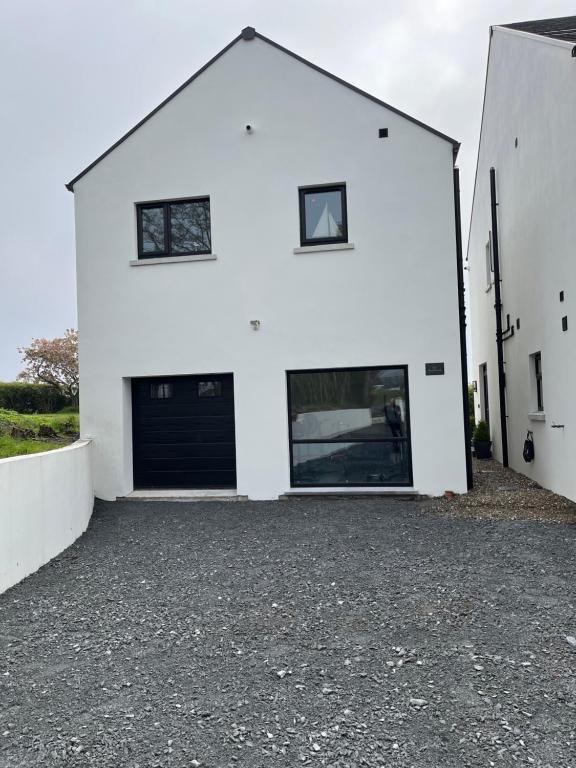 a white building with two windows and a garage at The Boathouse in Donaghadee