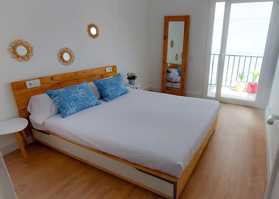 a bedroom with a large white bed with blue pillows at La puerta al Mar in Calafell