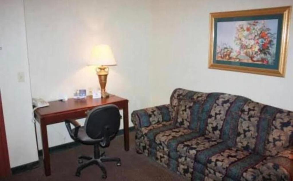 ein Hotelzimmer mit einem Sofa, einem Schreibtisch und einem Stuhl in der Unterkunft Ark Suites in Jonesboro