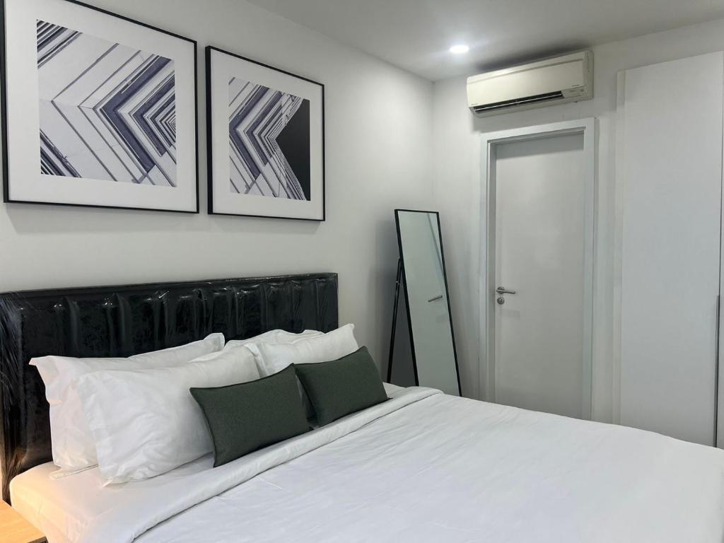 a bedroom with a white bed with two pictures on the wall at ImPian 1BR homestay in Phnom Penh