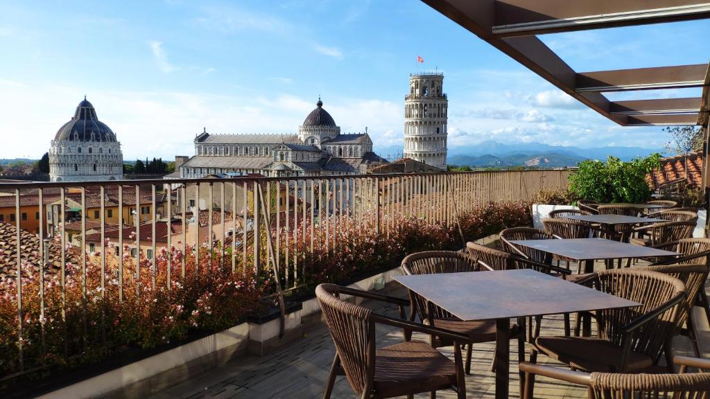 a patio with tables and chairs and a view of the city at Grand Hotel Duomo in Pisa