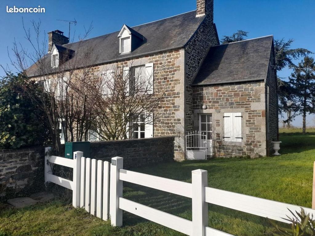 a white fence in front of a brick house at Le bien être aux forges in Céaux