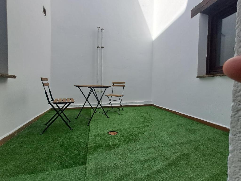 La Fragua I y II في Rebollar: غرفة مع طاولة وكراسي على أرضية خضراء