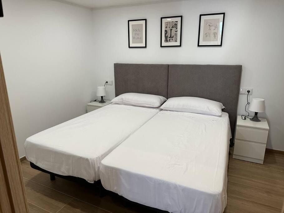 um quarto com uma grande cama branca com duas mesas de cabeceira em Apartamento Murcia San José B em Múrcia