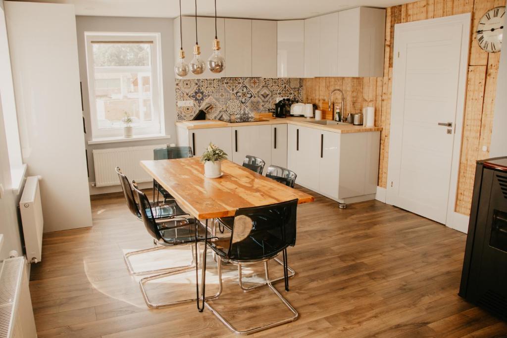 cocina y comedor con mesa de madera y sillas en Vītola apartamenti en Kuldīga