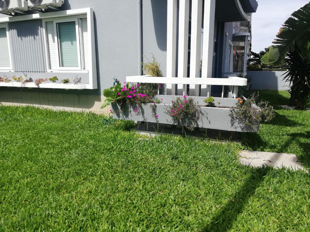 a white bench sitting in the grass in front of a house at Buddies Charm House in Aveiro