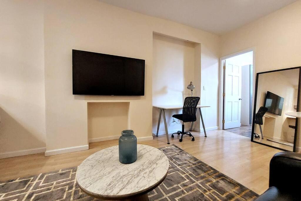 een woonkamer met een tafel en een tv aan de muur bij Large Queen Bed Apt with Workstation in New York