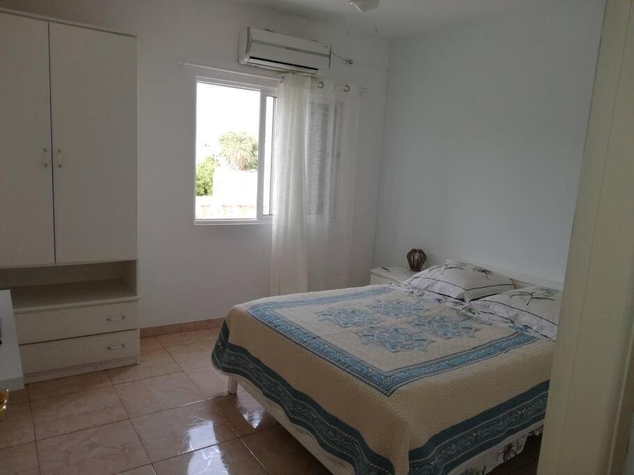 a white bedroom with a bed and a window at Casa Yô in Mindelo