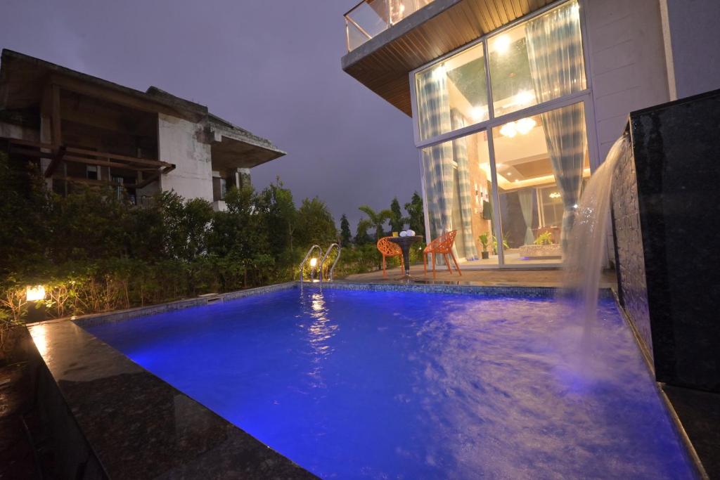 een zwembad voor een huis 's nachts bij Orchid Paradise Villa by Tropicana Stays in Lonavala