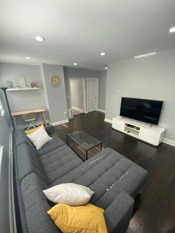 a living room with a couch and a flat screen tv at Luxury 3 bdr apt with backyard and off-street parking in Watertown