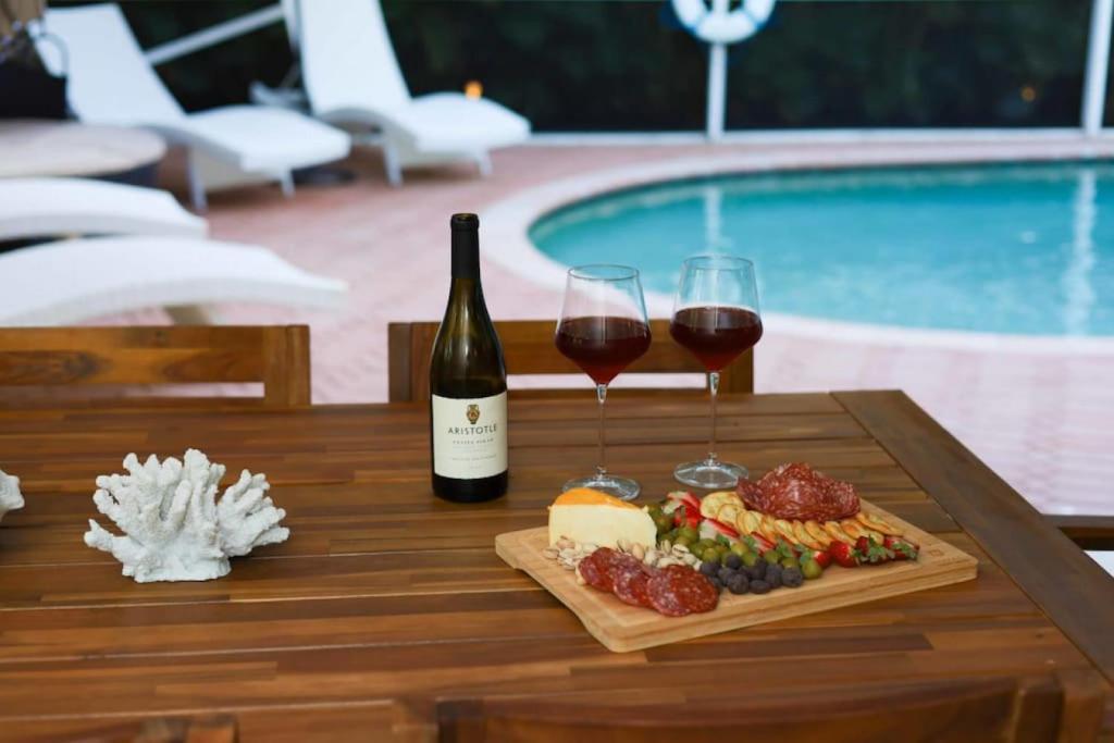 una mesa con dos copas de vino y un plato de comida en The Utopia Resort Dream Pool BBQ Outdoor Dining, en Greenacres City
