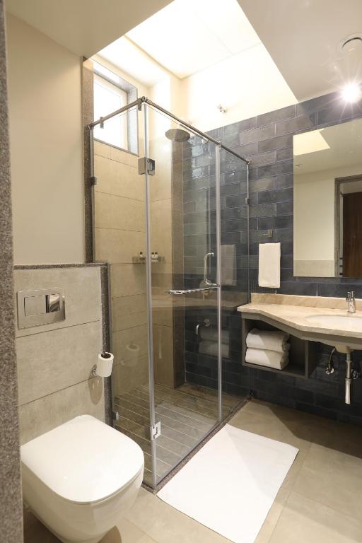 a bathroom with a shower and a toilet and a sink at Golden Fields Resort in Mulshi