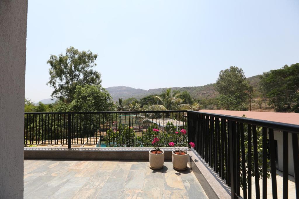 a balcony with two potted plants on a fence at Golden Fields Resort in Mulshi