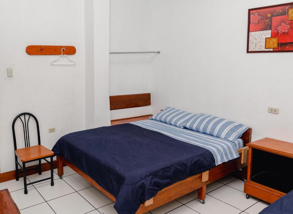 een slaapkamer met een bed en een stoel erin bij Yaki Hostel in Lima