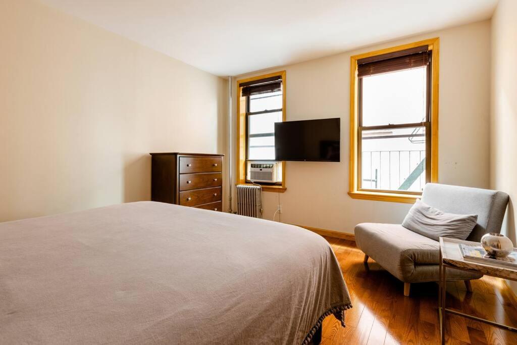 ニューヨークにある2 Bedroom King Bed Apartmentのベッドルーム(ベッド1台、椅子、テレビ付)