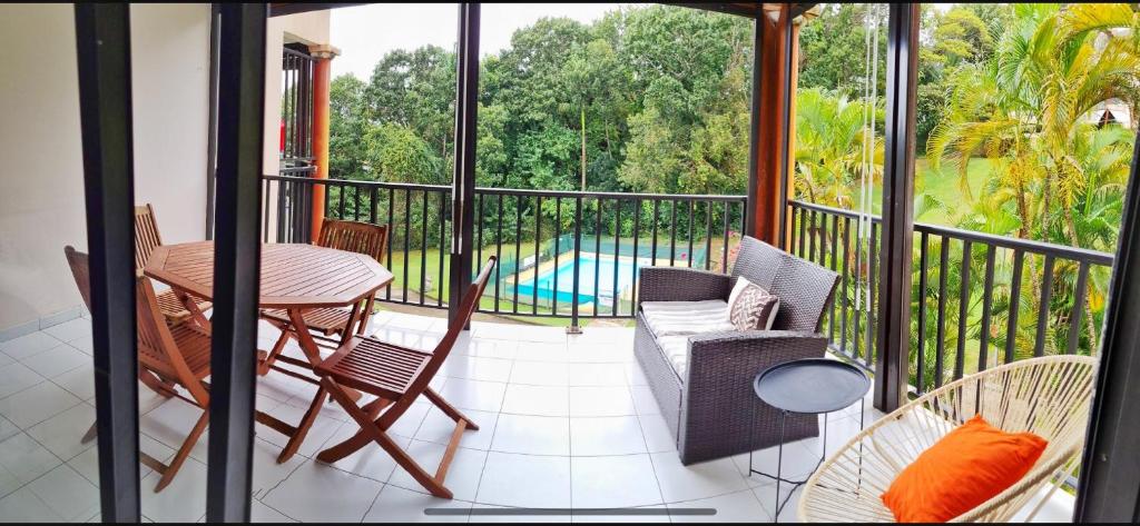 einen Balkon mit einem Tisch, Stühlen und einem Pool in der Unterkunft Appartement cosy dans résidence avec piscine in Fort-de-France