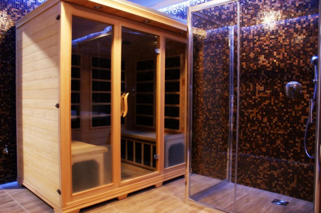 W łazience znajduje się prysznic ze szklanymi drzwiami. w obiekcie Alpejski Zieleniec w mieście Duszniki Zdrój