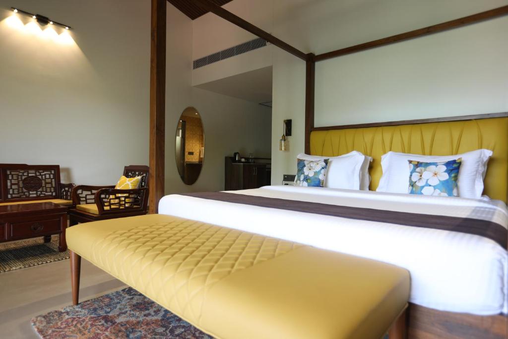 a bedroom with a large bed with a bench in it at Golden Fields Resort in Mulshi