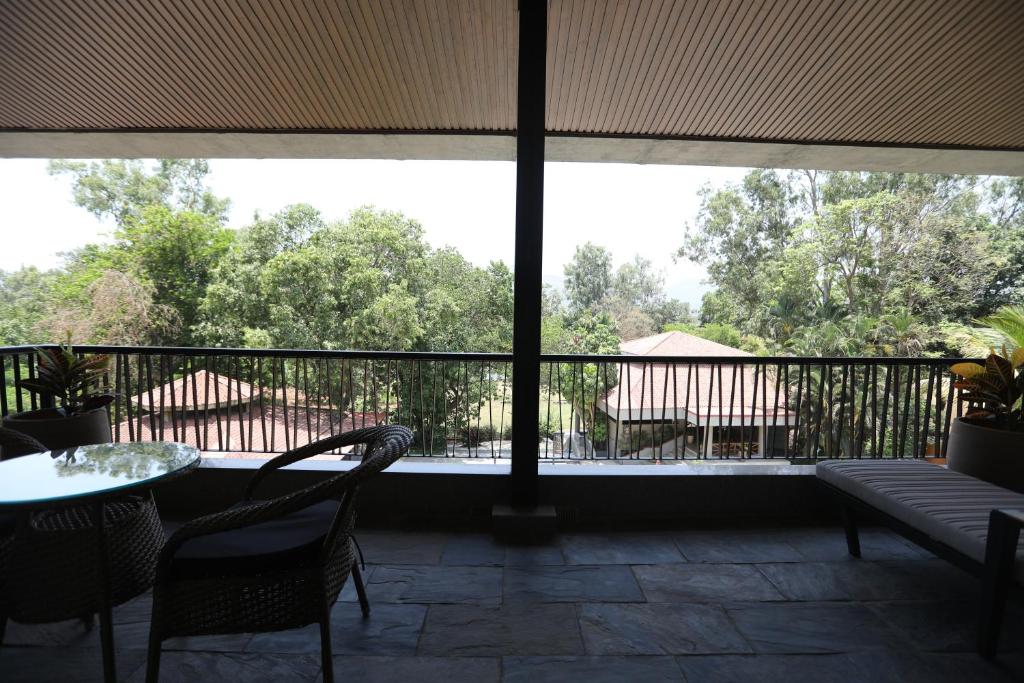 a porch with a table and chairs and a large window at Golden Fields Resort in Mulshi