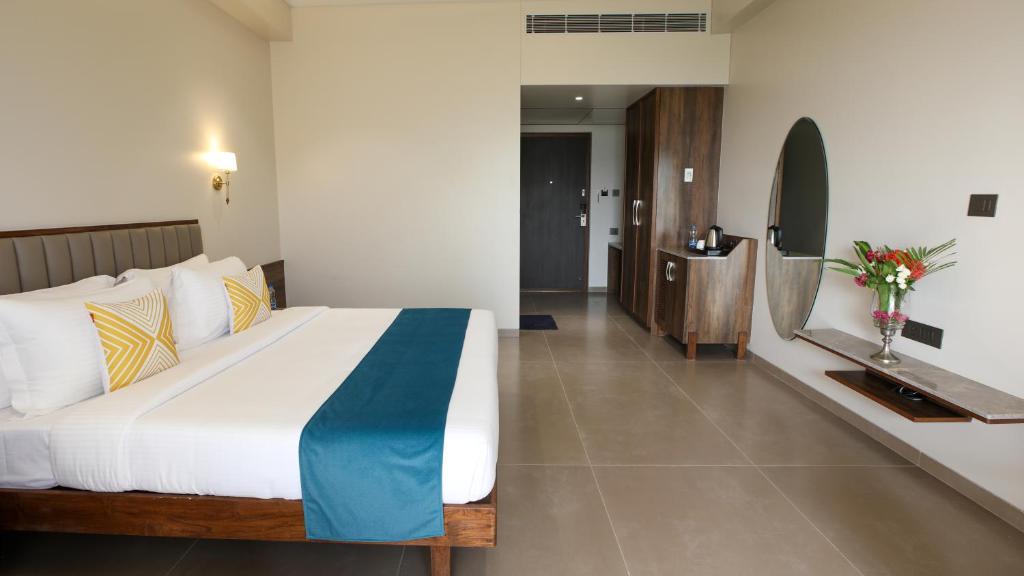 a bedroom with a large bed and a bathroom at Golden Fields Resort in Mulshi