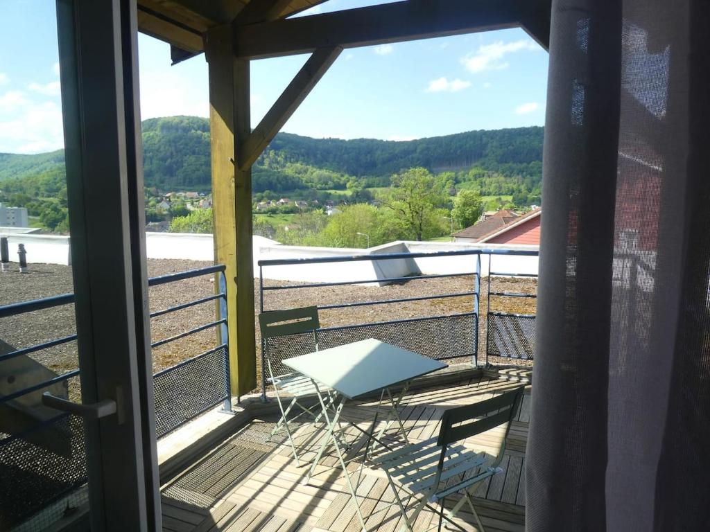 a balcony with a table and a view of the mountains at Chez Virginie in Ornans