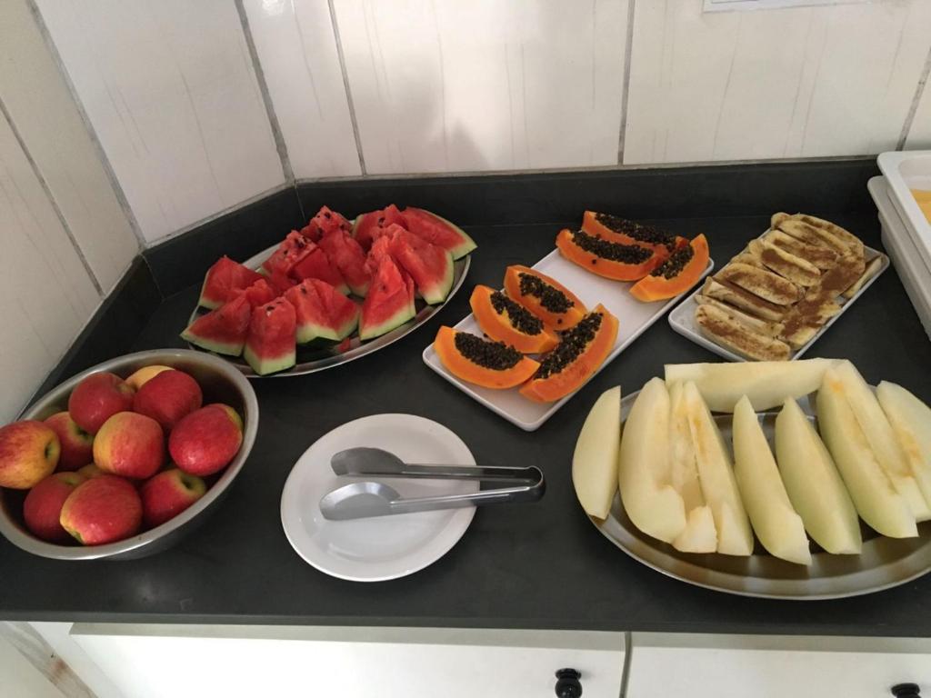 a black counter with three plates of food and fruit at Santos Hotel in Santos