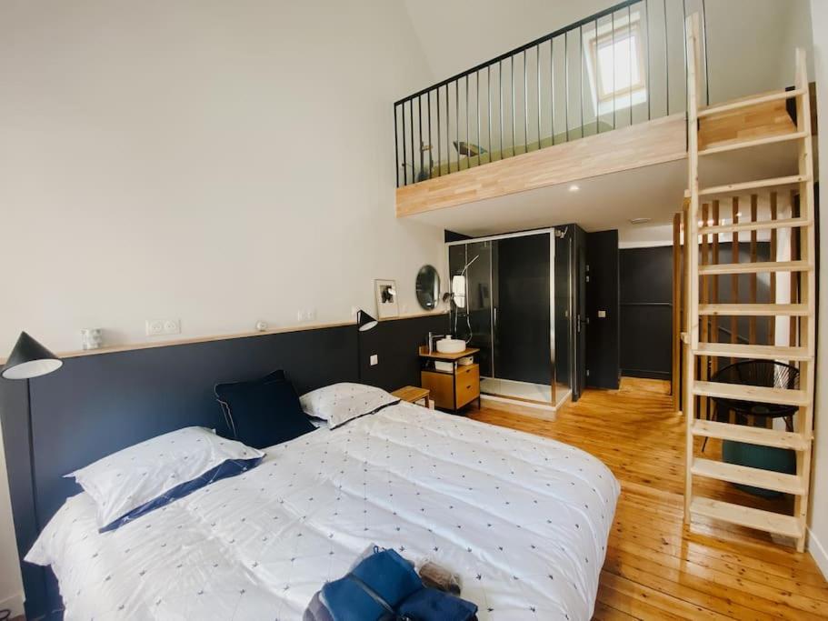 a bedroom with a large bed and a staircase at La Maison Rose Quartier des Arts - Hyper centre in Arras