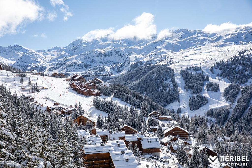 a ski resort covered in snow with mountains in the background at Antarès Méribel Resort & SPA in Les Allues