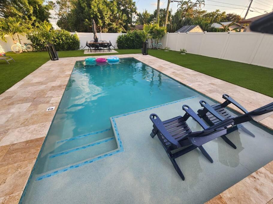 a swimming pool with two chairs and a table at Saltwater pool, FREE beach passes & GREAT location! in Boynton Beach