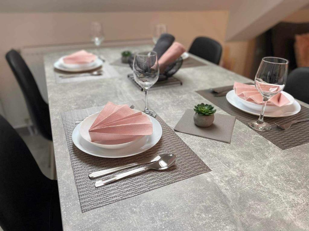 a table with plates and wine glasses on it at Csipke Residence 3 in Hajdúszoboszló