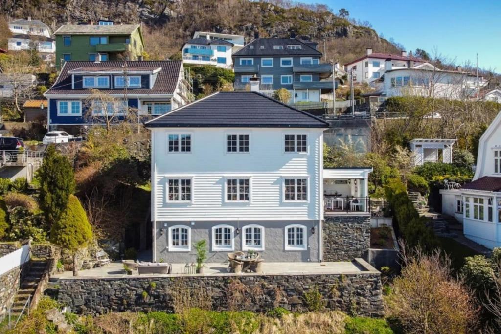 uma grande casa branca numa colina com casas em Dinbnb Homes I Luxury Villa with Hot Tub & Views em Bergen
