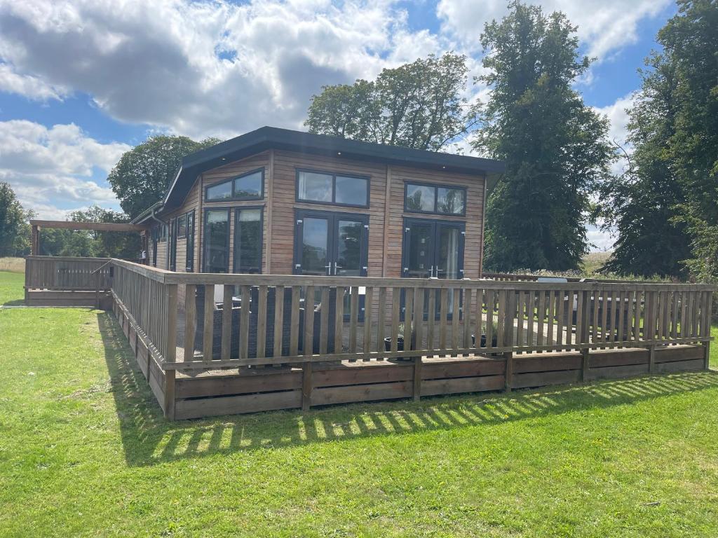 a small house with a wooden fence in the grass at Glasshouse lodge 