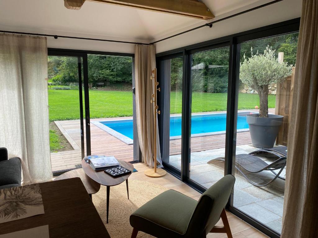 a living room with a view of a swimming pool at LE CLOS DAUPHINAIS Chez Laurette in Quévert