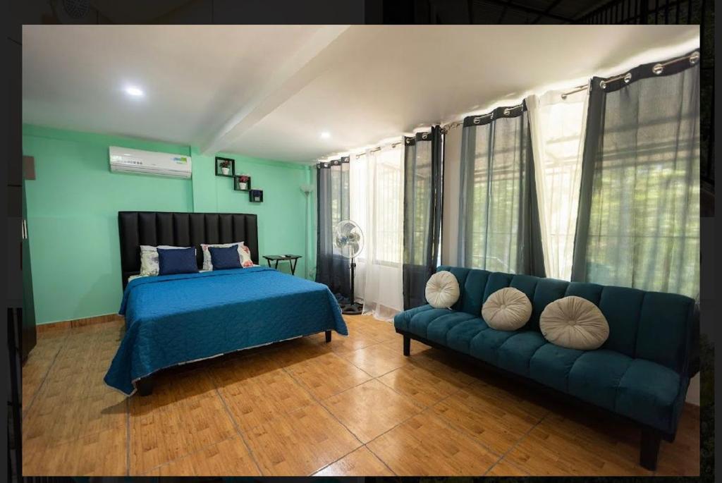 1 dormitorio con 1 cama azul y 1 sofá en CASA KENJY, en Quepos