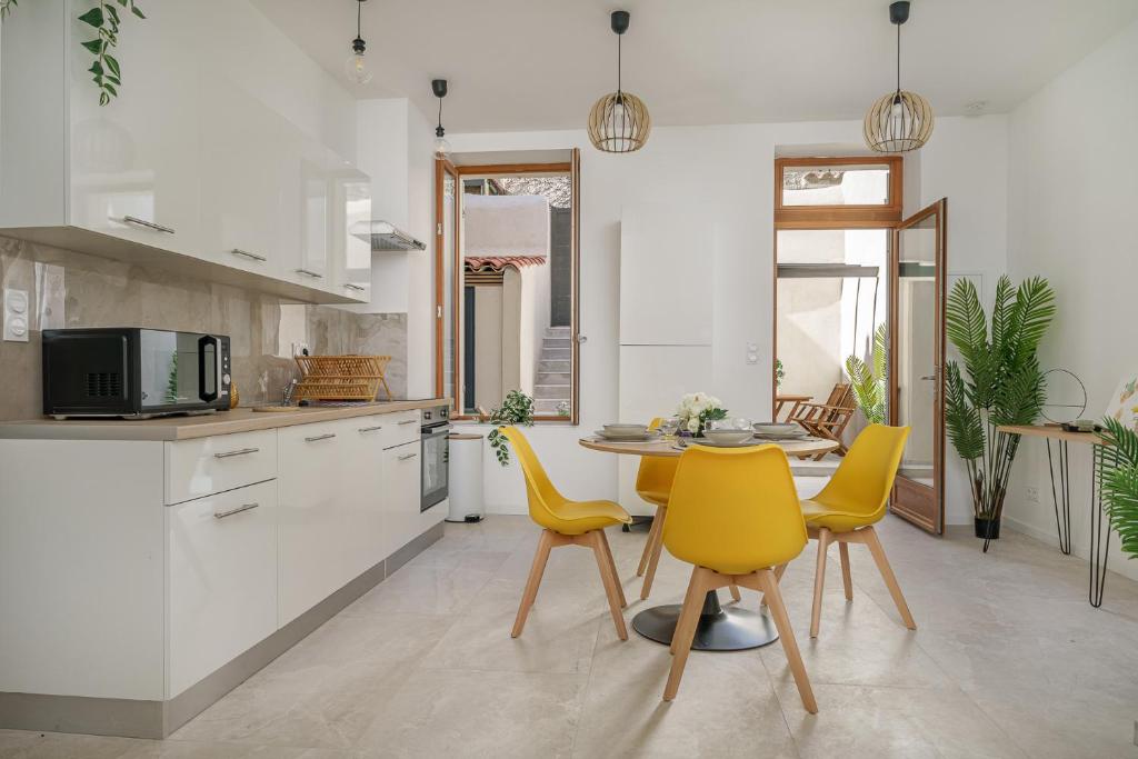 a kitchen with a table and yellow chairs at Sublime appartement avec Terrasse & Climatisation in Marseille