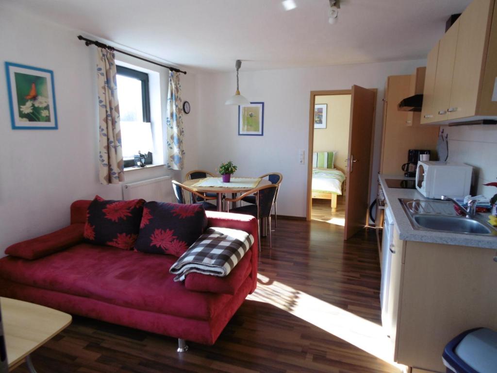 a living room with a red couch and a kitchen at Ferienwohnung Schäfer in Waldbreitbach