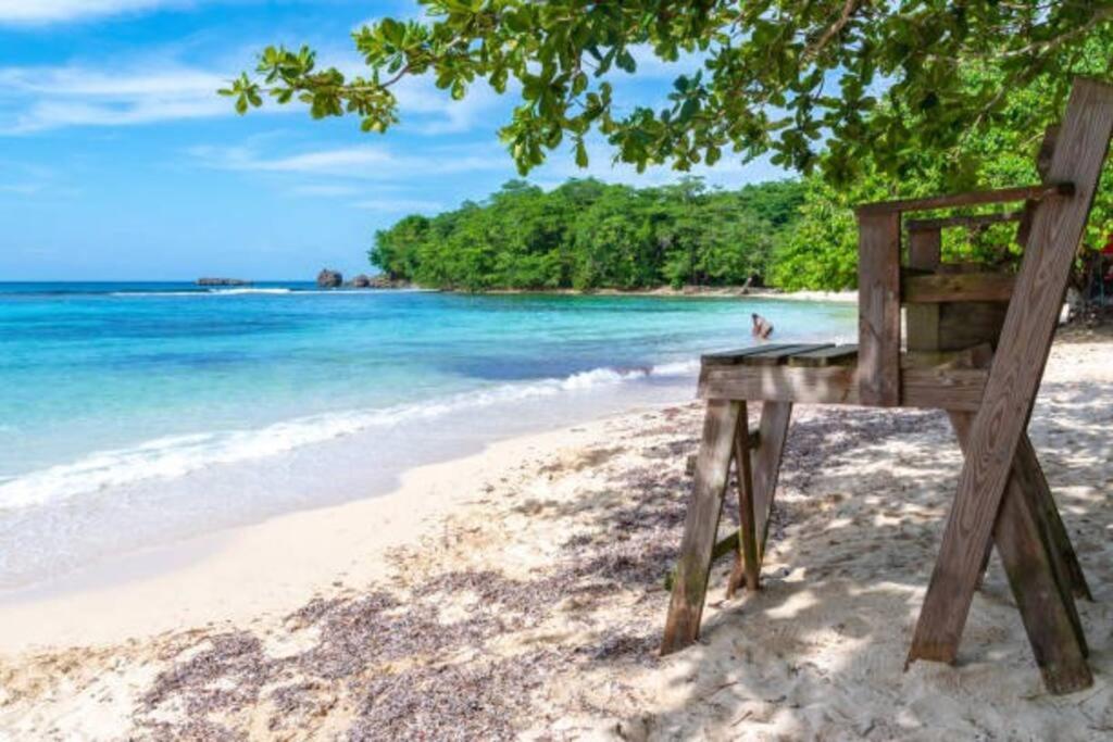 una silla de madera sentada en una playa junto al océano en Full 3 BD Home w/Oceanviews and AC in all rooms., en Manchioneal