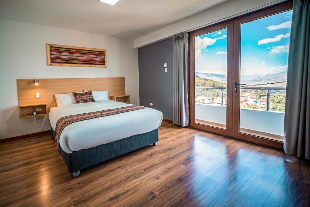 a hotel room with a bed and a large window at Ayni Cusco Hotel in Cusco