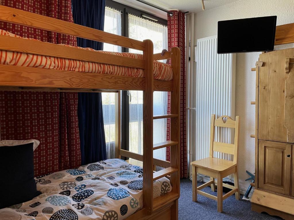 - une chambre avec des lits superposés, une télévision et une chaise dans l'établissement Studio Économique 13m² pour 2 personnes au pied des pistes, Croisette, Les Menuires - FR-1-452-285, aux Menuires