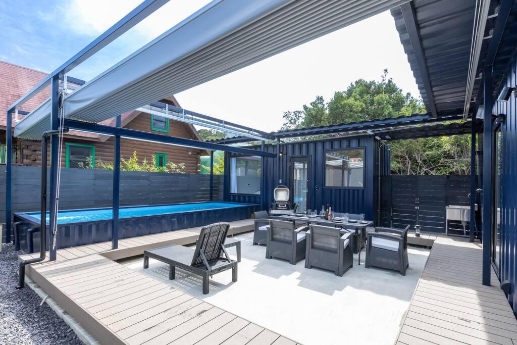 patio ze stołem i krzesłami oraz basenem w obiekcie 淡路島 Villa Paddle - Self Check-In Only w mieście Sumoto