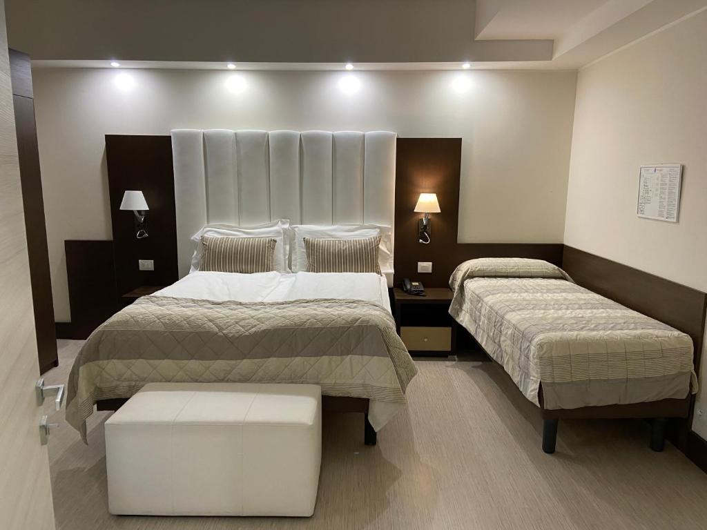 a hotel room with two beds and two tables at International Beach Hotel in Caorle