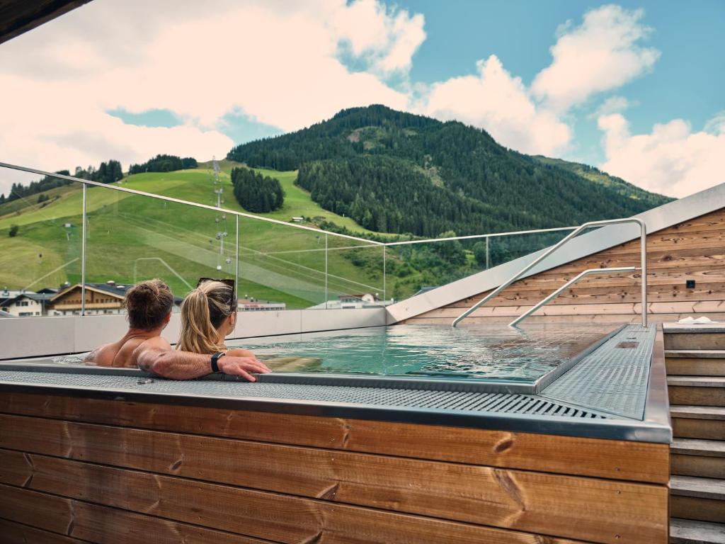 a man and a woman sitting in a pool of water at Hotel Hasenauer in Saalbach Hinterglemm