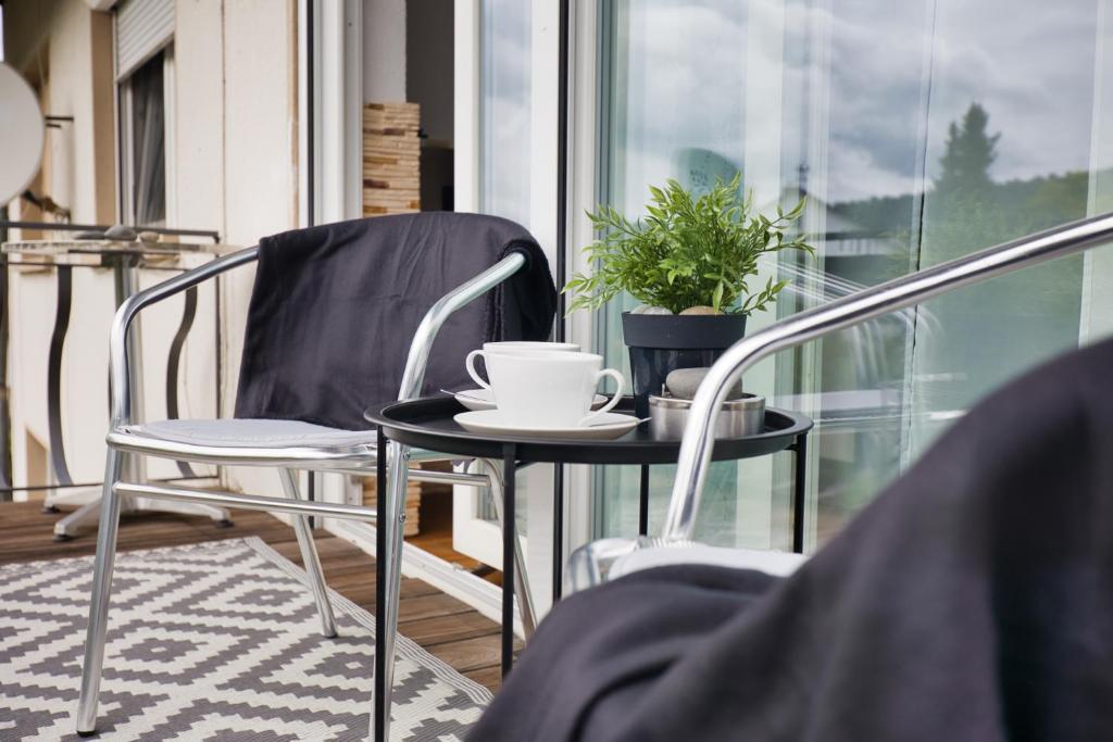 einen Tisch und Stühle auf einem Balkon mit einer Tasse Kaffee in der Unterkunft Holiday Apartment NAMASTAY in Küssaberg