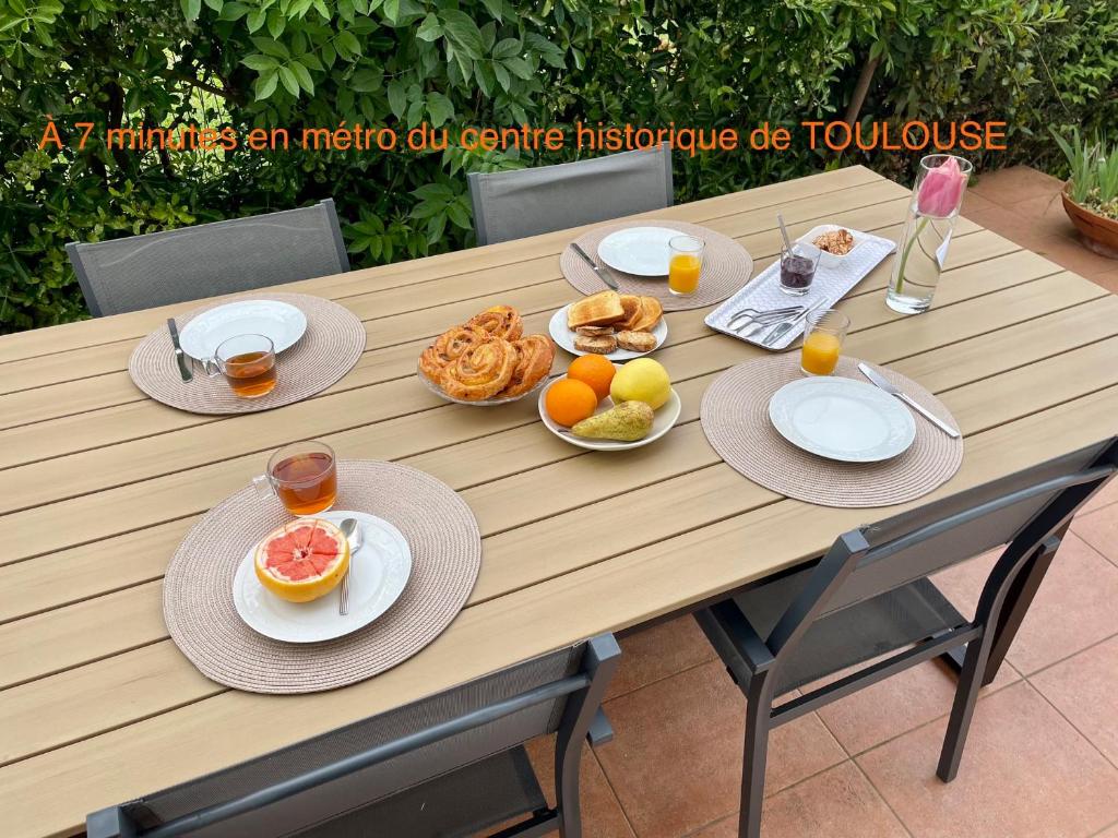 a wooden table with plates of food on it at 50 m2 4 couchages T2 au calme, lumineux, confortable, cosy, climatisé, privatif avec parking gratuit et terrasse in Toulouse