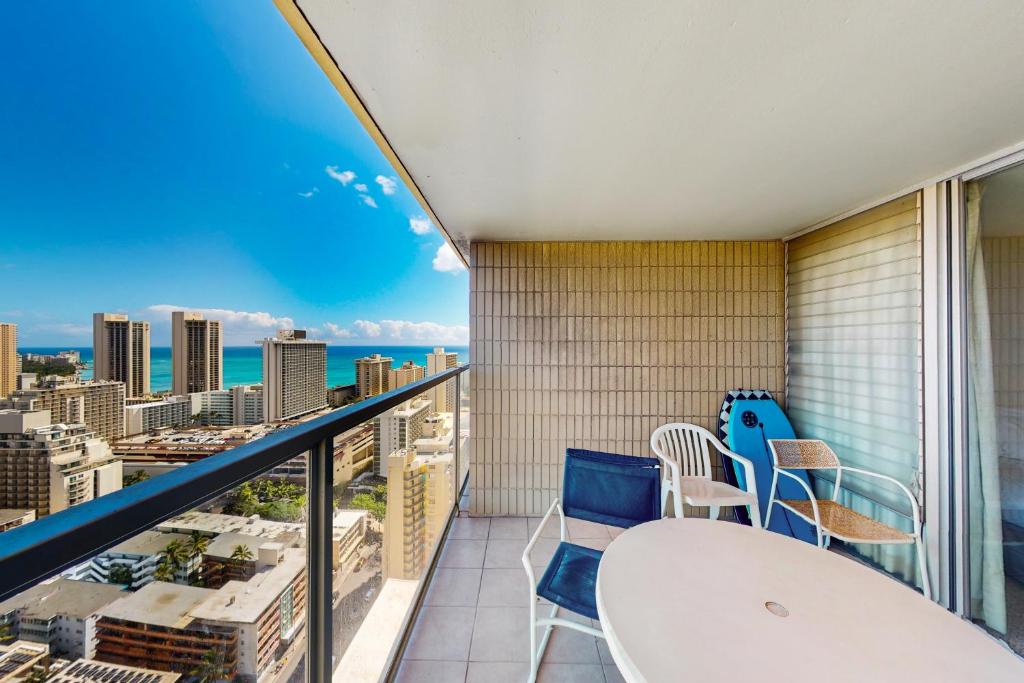 a balcony with a table and chairs and a view of the city at Island Colony 3519 - 30 night minimum in Honolulu