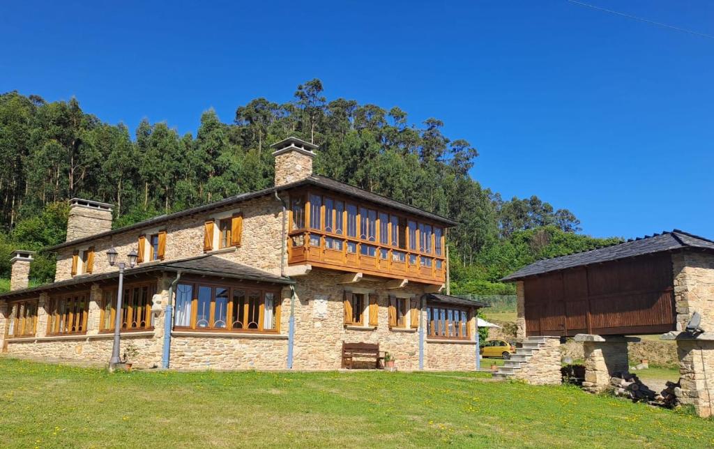 un gran edificio de piedra con un balcón en un campo en Casa Almoina, en Viveiro