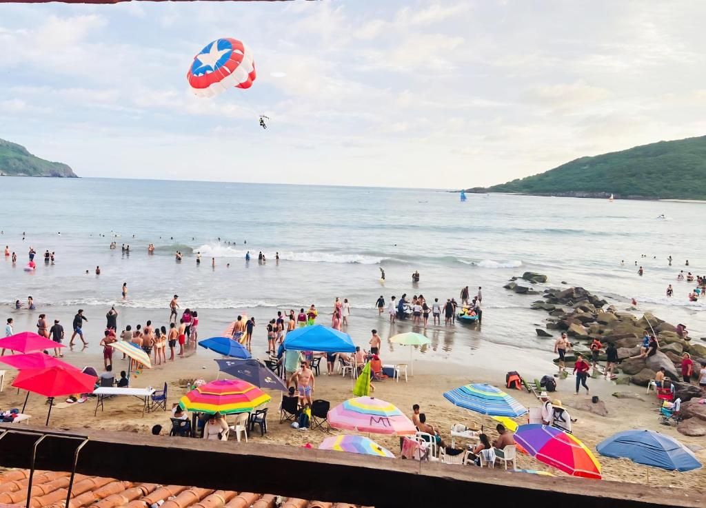 grupa ludzi na plaży z parasolami w obiekcie Increíble Depa Frente al Mar w mieście Mazatlán