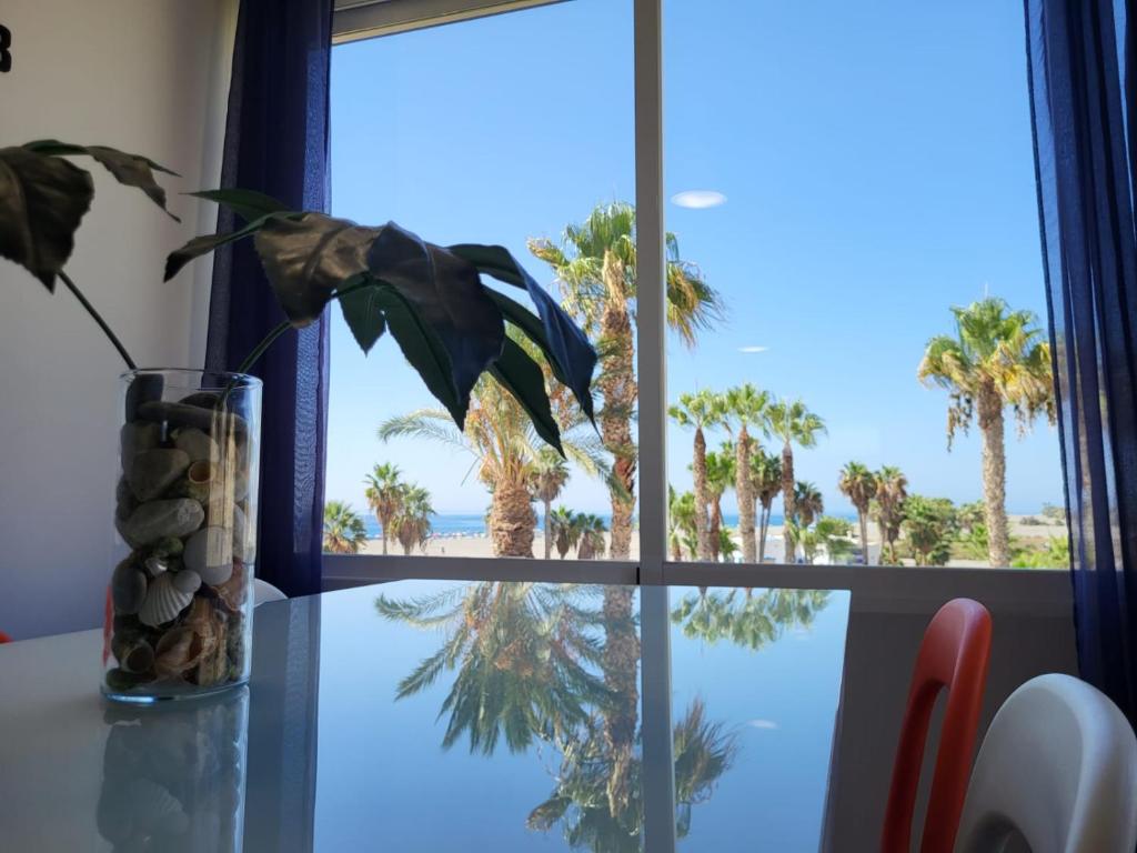 - une fenêtre avec vue sur la plage et les palmiers dans l'établissement Motril, primera línea de playa., à Motril