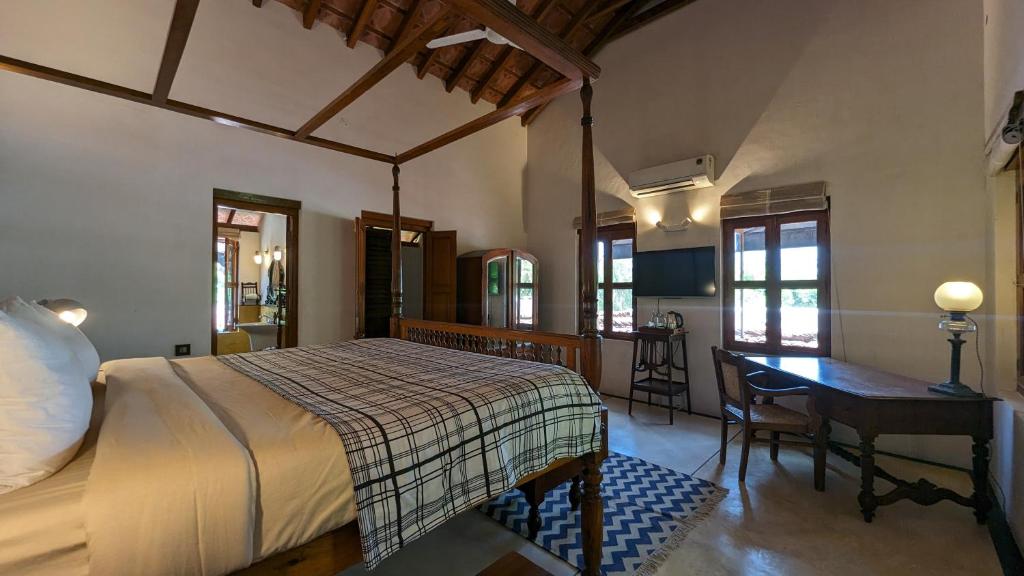 1 dormitorio con cama, escritorio y mesa en Thanga House by LuxUnlock Private Villas, en Tarangambādi